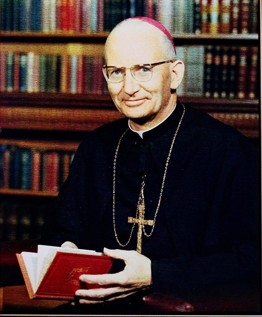 Cardinal James Robert Knox holding a book in the library